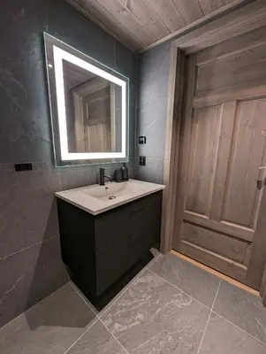 a bathroom with a sink and a mirror and a door at Ski in/out Appartment Hemsedal in Hemsedal