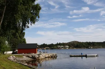 a boat dock with a red building on the water at Åkviktunet hytte Sør in Averoy