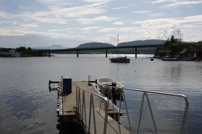 a boat on the water with a bridge in the background at Åkviktunet hytte Sør in Averoy