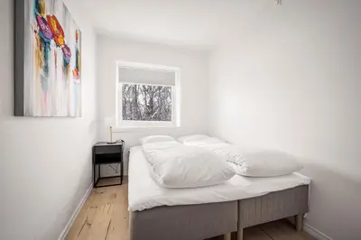 a bedroom with a bed with white sheets and a window at Gullstein in Geilo