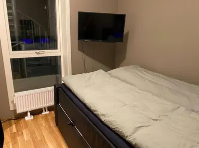 a bedroom with a bed and a television on the wall at Strøken leilighet inkl parkeringskjeller. in Trondheim