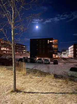 a building with cars parked in a parking lot at night at Strøken leilighet inkl parkeringskjeller. in Trondheim