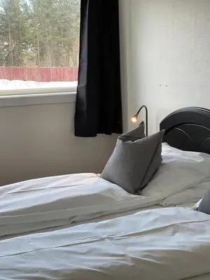 a bed with white sheets and pillows next to a window at Oppdalsporten Motell in Oppdal