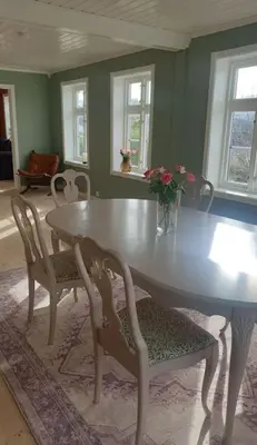 a dining room table with two chairs and a vase of flowers at Romslig og særegent hus in Skodje