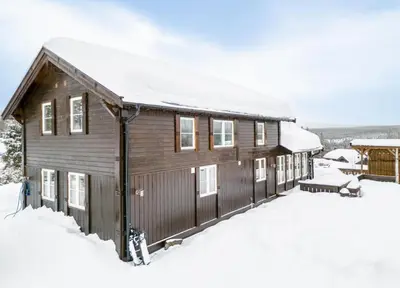 a wooden cabin with snow on the roof at A wonderful estate of two houses for all seasons! in Trysil