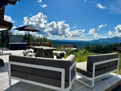 a patio with a couch and a table and an umbrella at Flott moderne hytte i Holterdalen, 4 soverom, 2 bad, Jacuzzi, garasje in Rauland
