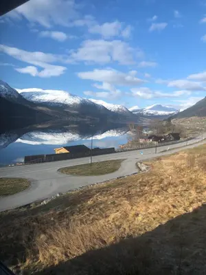 a road with a snow covered mountain in the background at Jølster Lake View in Årdal