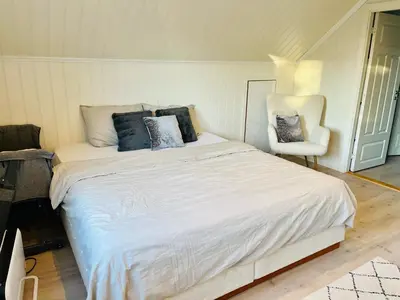 a bedroom with a large white bed and a chair at A beautiful 3-bedroom apartment with stunning views and free parking in Bergen