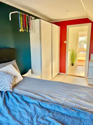 a bedroom with a blue bed and a red wall at A beautiful 3-bedroom apartment with stunning views and free parking in Bergen