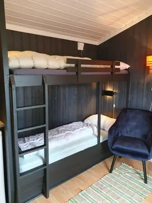 a bedroom with two bunk beds and a chair at Bjørgebu Camping AS in Mysusæter
