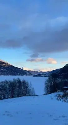 a snow covered field with a lake and some mountains at New appartment in Lom inkl bedding in Lom