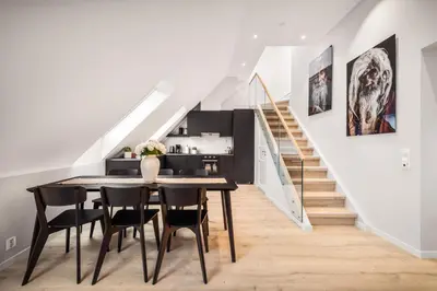 a dining room with a table and chairs and a staircase at Allmenningen Apartments in Bergen