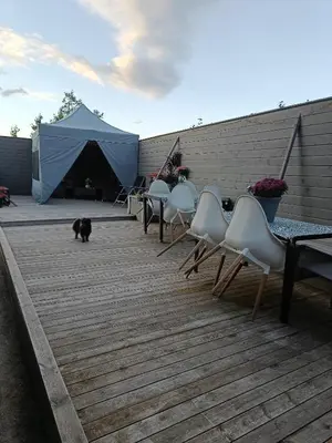 a black cat walking on a deck with chairs and a tent at 3-roms leilighet, innsjekk uten vert. Egen inngang in Ålesund