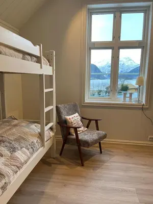 a bedroom with bunk beds and a chair and a window at Skogly - det gode livet på landet in Stryn