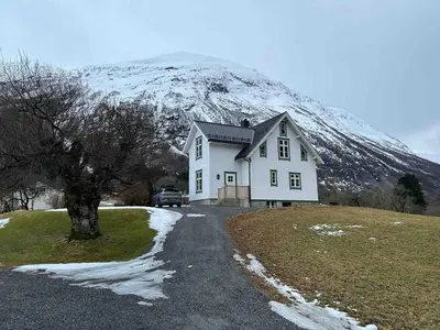 a house in front of a snow covered mountain at Skogly - det gode livet på landet in Stryn