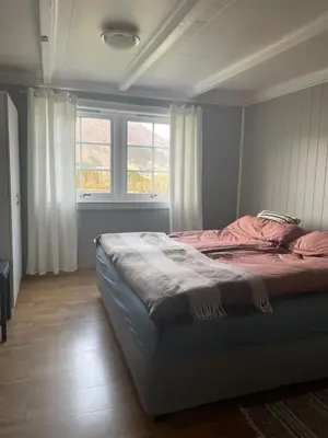 a bedroom with a bed in a room with windows at Krokenes in Sylte