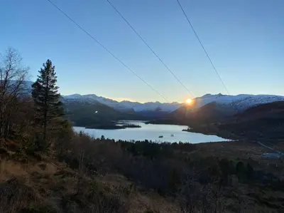 a view of a lake with the sun setting in the mountains at Ladebua in Brunstad