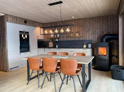 a kitchen with a table and chairs and a fireplace at Ladebua in Brunstad