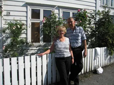a man and a woman standing in front of a white fence at 