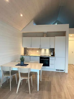 a kitchen with white cabinets and a table and chairs at Rorbu i Bud Havn in Bud