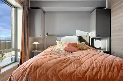 a bedroom with a large bed and a large window at Riddertunets lune leilighet - dyr tillatt in Beitostøl