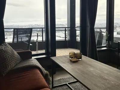a living room with a couch and a table and windows at Riddergaardens panorama in Beitostøl