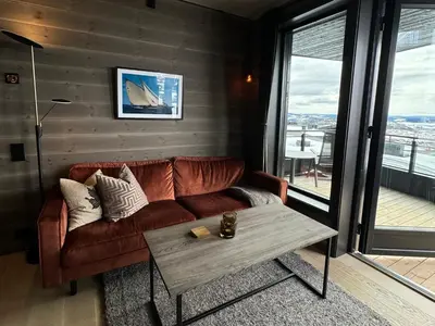 a living room with a brown couch and a table at Riddergaardens panorama in Beitostøl