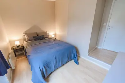 a bedroom with a bed with blue sheets and a window at Supersentralt Bergen sentrum in Bergen