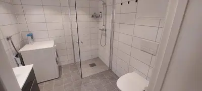 a bathroom with a shower and a toilet and a sink at Bergen city apartment in Bergen
