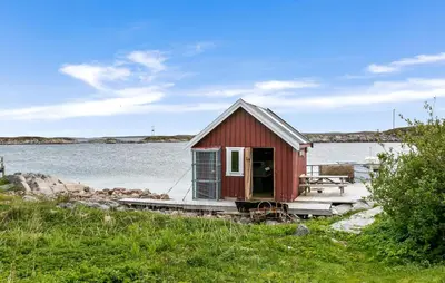 a small red house on the shore of a body of water at Cozy Home In Norddyrøy With Kitchen in Sætra