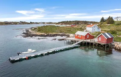 a dock with houses and a boat in the water at Cozy Home In Norddyrøy With Kitchen in Sætra