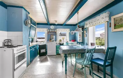 a kitchen with blue walls and a table and chairs at Cozy Home In Norddyrøy With Kitchen in Sætra