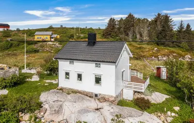 a small white house on top of a rock at Cozy Home In Norddyrøy With Kitchen in Sætra