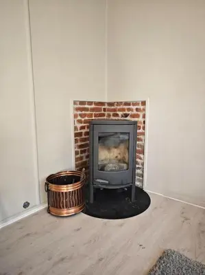 a living room with a brick fireplace with a stove at Rekkehus Tyssedal Trolltunga in Tveit