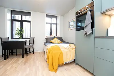 a bedroom with a bed and a table and a desk at Sentrumsnær studioleilighet! in Trondheim