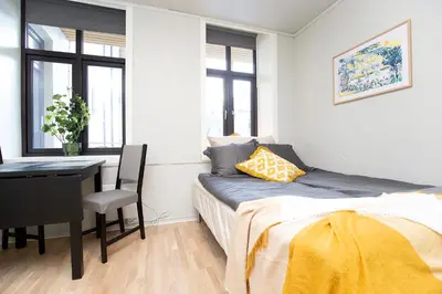 a bedroom with a bed and a table and a desk at Sentrumsnær studioleilighet! in Trondheim