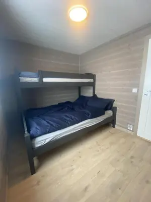 a bedroom with a bunk bed with blue sheets at Nydelig hytte ved Voss Ski og Tursenter in Giljane