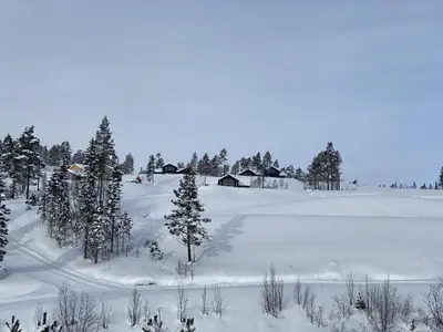 a snow covered field with trees and a barn at Nydelig hytte ved Voss Ski og Tursenter in Giljane
