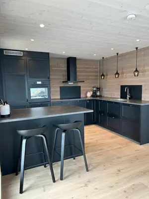 a kitchen with black cabinets and black counter stools at Nydelig hytte ved Voss Ski og Tursenter in Giljane