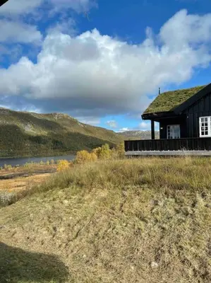 a house on a hill next to a body of water at Heimro in Torvetjørn