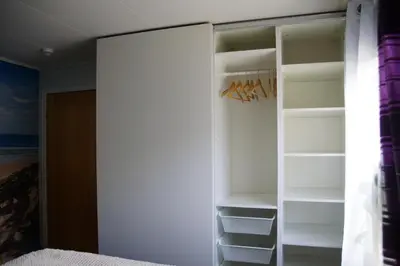 a closet with white doors and shelves in a bedroom at Cozy room in a house with a garden on the island of Askøy, near Bergen in Askøy