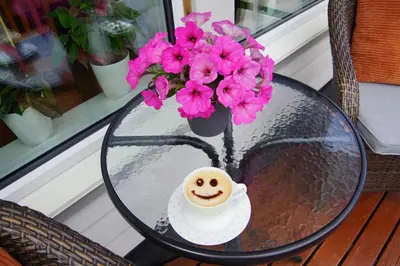 a table with a cup of coffee and flowers on it at Cozy room in a house with a garden on the island of Askøy, near Bergen in Askøy