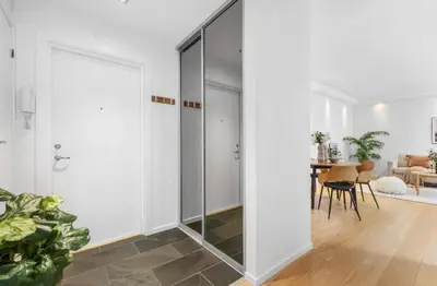 a glass pivot door in a living room with a table at Nydelig leilighet på Nordnes! in Bergen