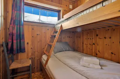 a bunk bed in a wooden room with a ladder at Halne Fjellstugu in Maurset