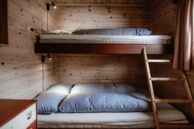 two bunk beds in a wooden room with a ladder at Halne Fjellstugu in Maurset
