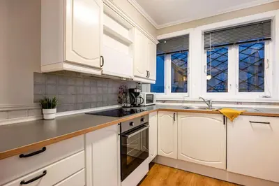 a white kitchen with white cabinets and windows at Central stay apartment - 302 in Bergen