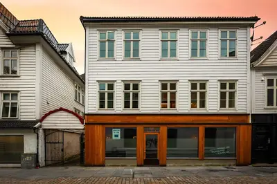 a large white building with wooden doors next to other buildings at Central stay apartment - 302 in Bergen
