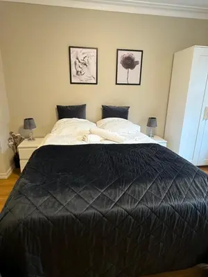 a bedroom with a large black bed with two lamps at Central stay apartment - 303 in Bergen