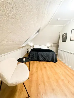 a attic bedroom with a bed and two chairs at Central stay apartment - 401 in Bergen
