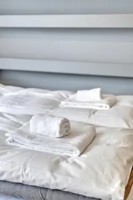 two white towels sitting on top of a white bed at Cozy Studio Retreat in Bergen
